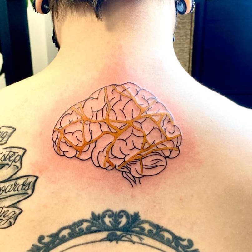 Tattoo of a brain with gold veins on an upper back